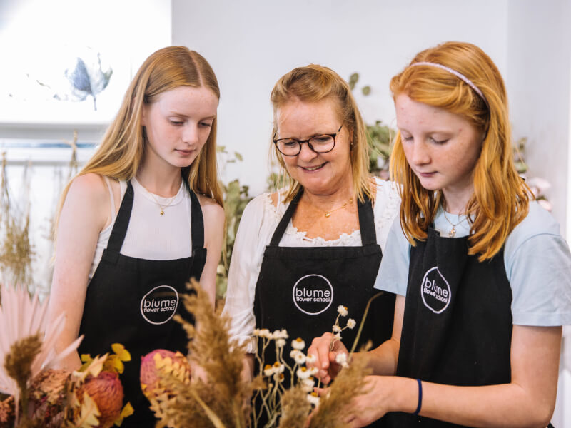 A mum and her daughters make a dried floral arrangement.